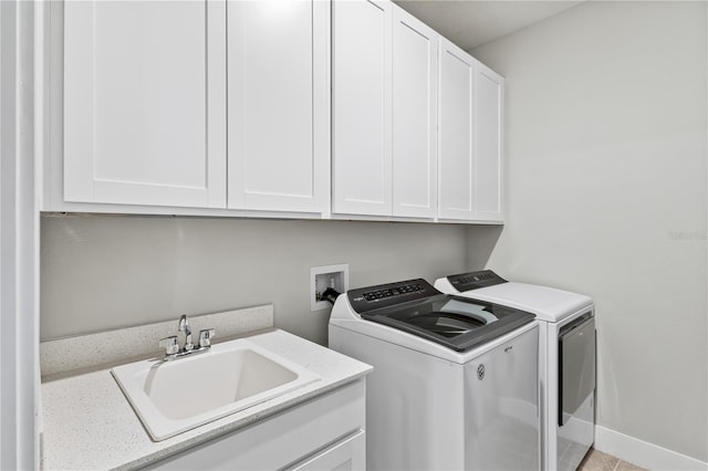 laundry area featuring independent washer and dryer, a sink, cabinet space, and baseboards