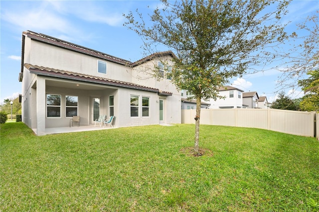 back of house featuring a patio, stucco siding, a lawn, roof mounted solar panels, and fence