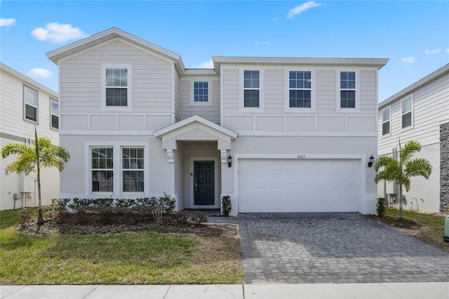 view of front facade featuring an attached garage, decorative driveway, and stucco siding