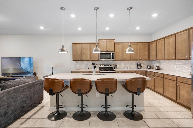 kitchen with appliances with stainless steel finishes, brown cabinetry, and a breakfast bar area