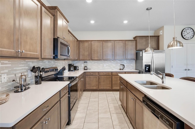 kitchen featuring decorative light fixtures, stainless steel appliances, a sink, and light countertops