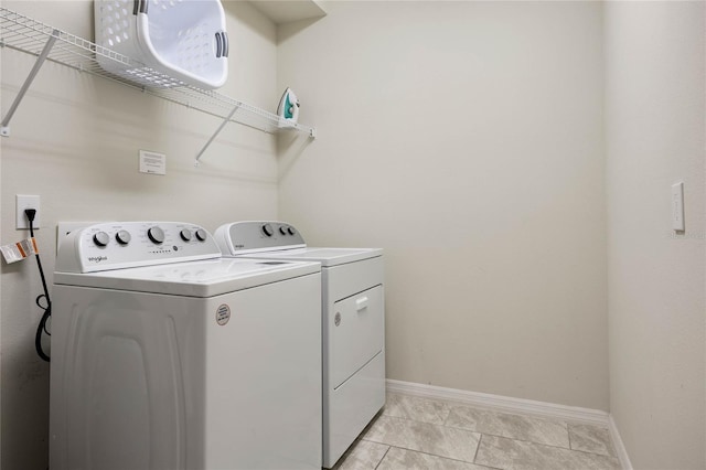 washroom featuring laundry area, baseboards, washing machine and clothes dryer, and light tile patterned floors