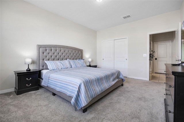 bedroom with baseboards, visible vents, a closet, and light colored carpet