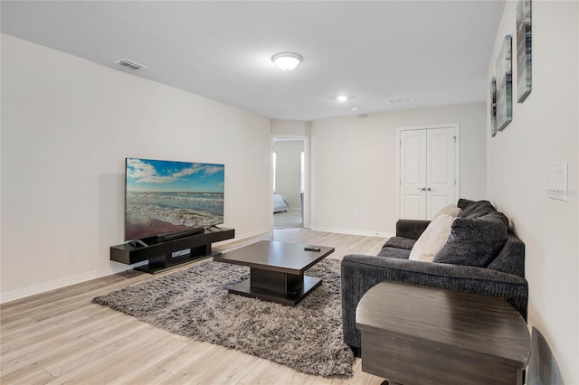 living room with wood finished floors, visible vents, and baseboards