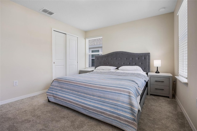 carpeted bedroom featuring a closet, visible vents, and baseboards