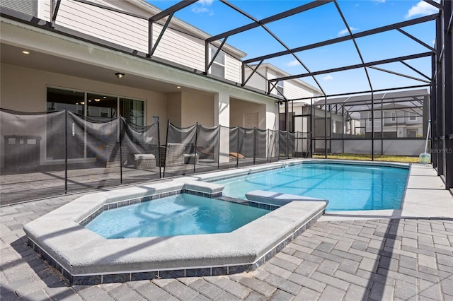 view of pool with a pool with connected hot tub, a patio, and a lanai