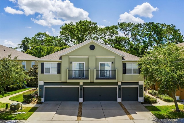 view of front facade with an attached garage, roof with shingles, concrete driveway, and stucco siding