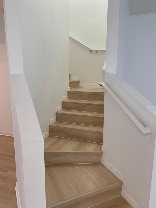 staircase featuring wood finished floors and baseboards