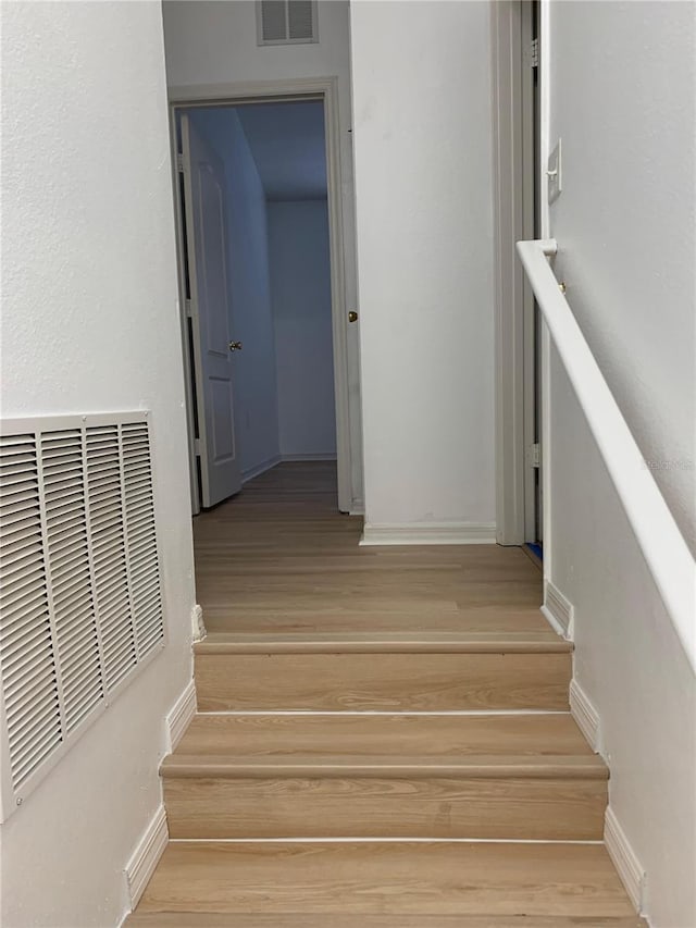 stairs with visible vents, baseboards, and wood finished floors