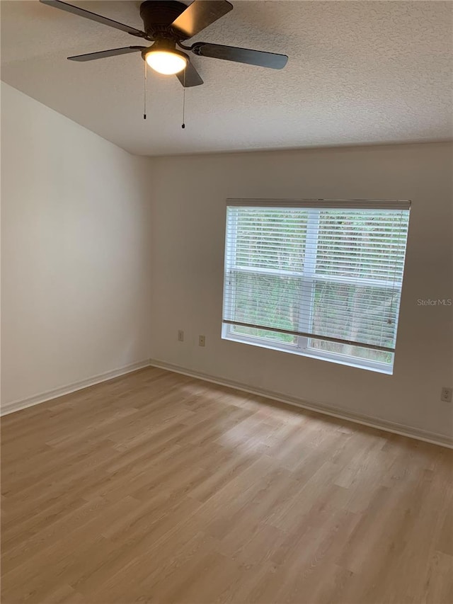 spare room featuring a textured ceiling, ceiling fan, baseboards, and light wood-style floors