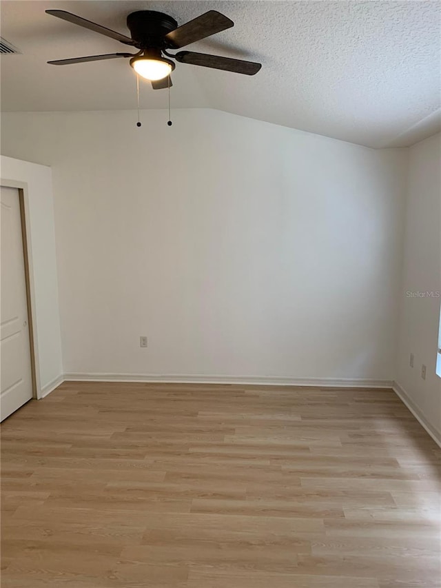 spare room with a textured ceiling, baseboards, visible vents, and light wood-style floors