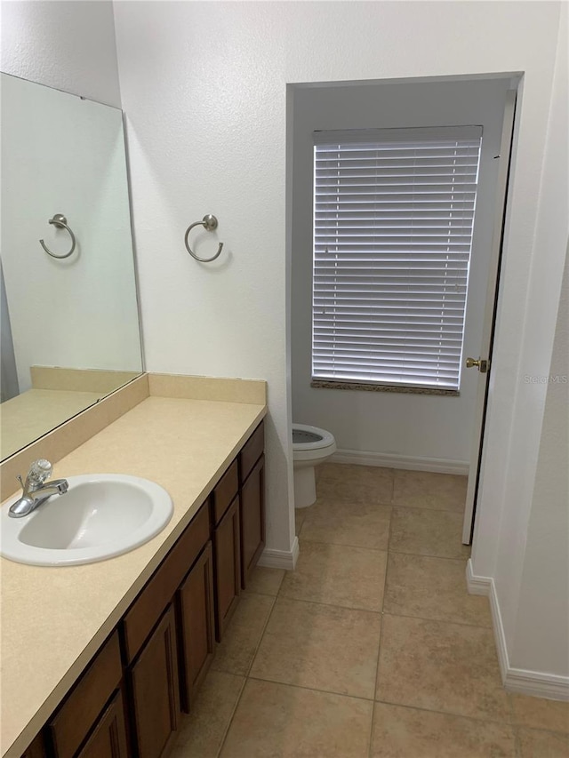 bathroom featuring tile patterned flooring, baseboards, vanity, and toilet