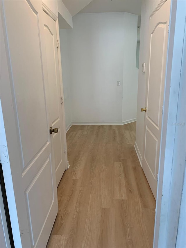 hallway featuring light wood-type flooring and baseboards