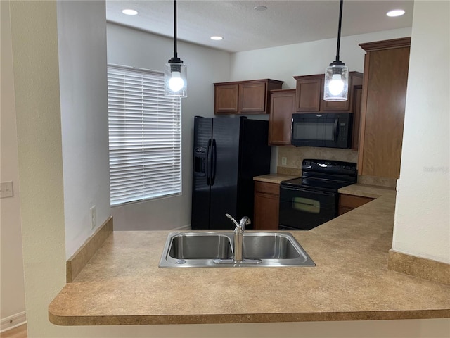 kitchen with black appliances, light countertops, a sink, and decorative light fixtures