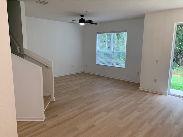 unfurnished living room featuring a ceiling fan, visible vents, baseboards, stairway, and light wood-type flooring