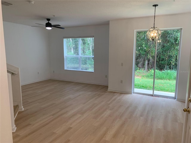 unfurnished living room with light wood finished floors, baseboards, visible vents, and ceiling fan with notable chandelier