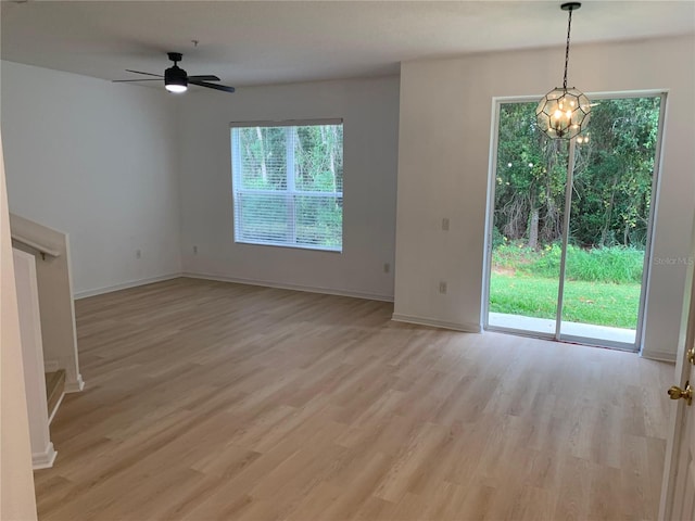 unfurnished living room featuring light wood-type flooring, baseboards, and ceiling fan with notable chandelier