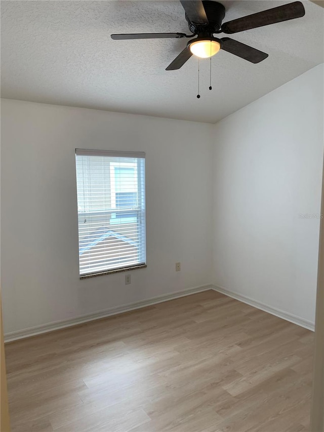 unfurnished room with a ceiling fan, light wood-type flooring, a textured ceiling, and baseboards