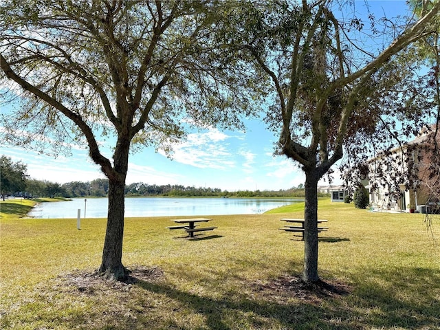 view of home's community with a water view and a lawn