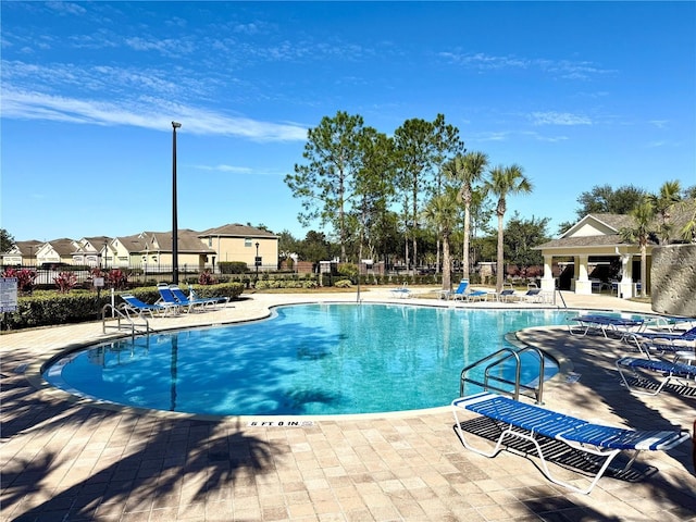 community pool with a patio area and fence