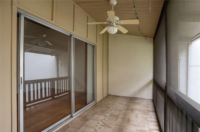 unfurnished sunroom with rail lighting and a ceiling fan