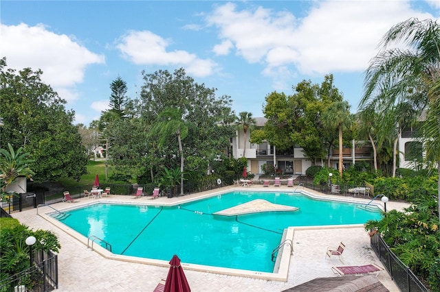 community pool with a patio and fence