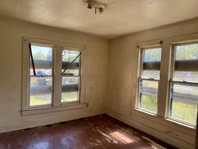 spare room featuring dark wood finished floors and baseboards