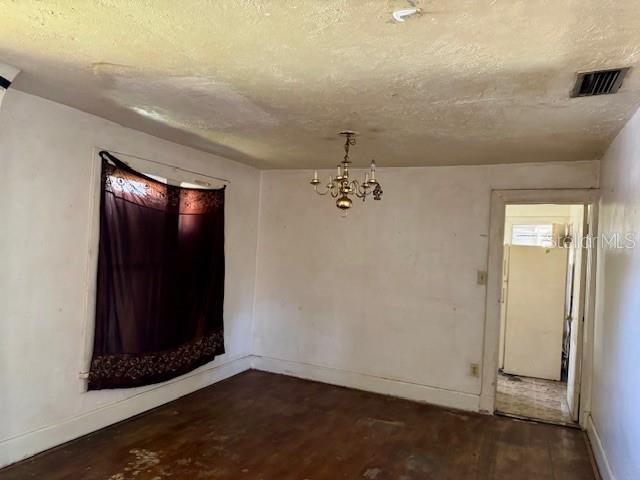 spare room featuring a textured ceiling, visible vents, and wood finished floors