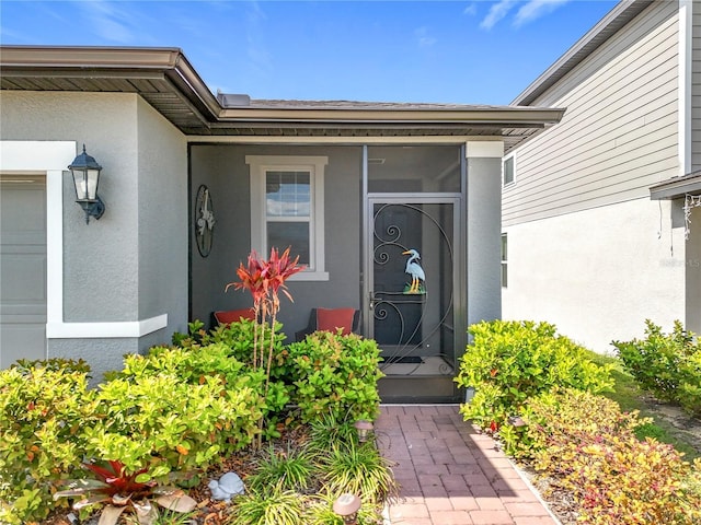 doorway to property featuring a garage and stucco siding