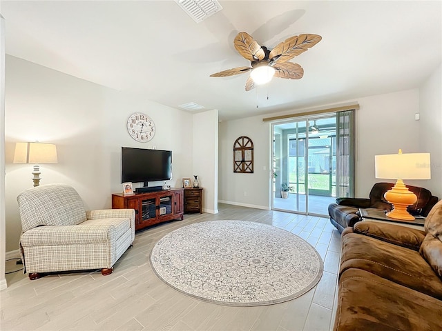 living room featuring light wood-style floors, ceiling fan, visible vents, and baseboards