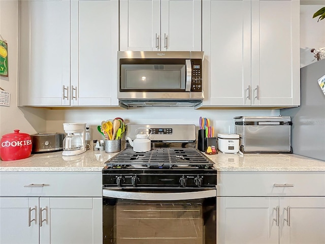 kitchen featuring light stone countertops, appliances with stainless steel finishes, and white cabinets