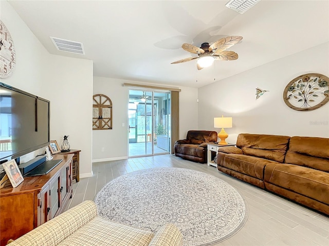 living room featuring baseboards, ceiling fan, visible vents, and wood finished floors