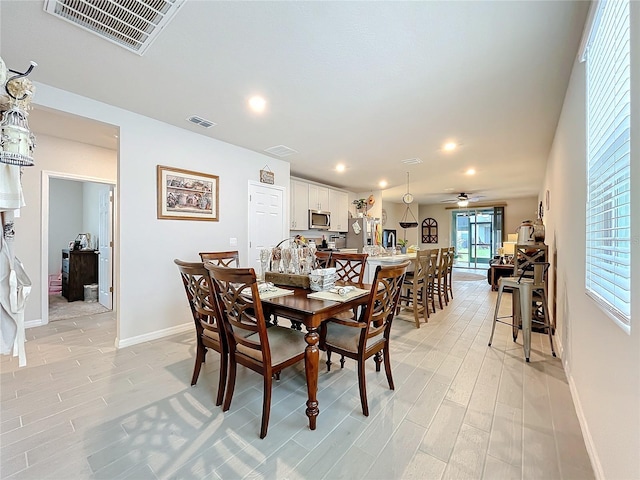 dining area with a ceiling fan, visible vents, light wood finished floors, and baseboards