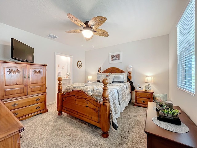 bedroom with visible vents, ceiling fan, light carpet, and ensuite bathroom