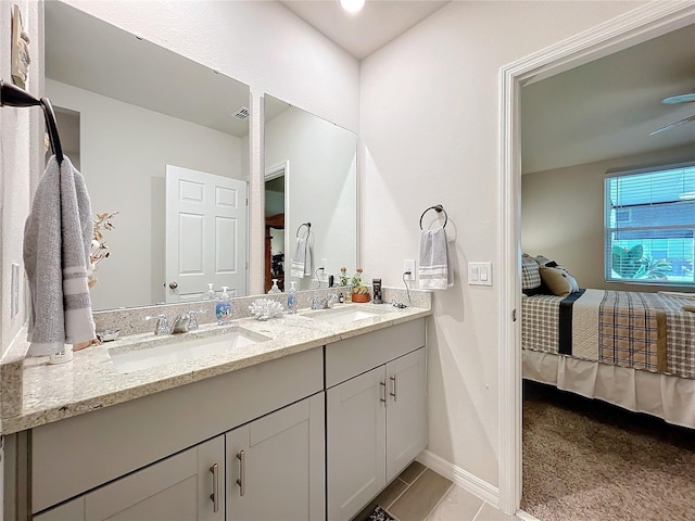 ensuite bathroom with double vanity, ensuite bath, baseboards, and a sink