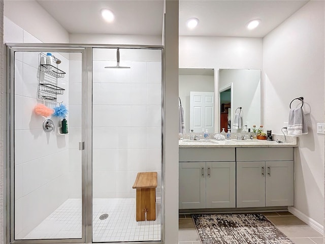 full bathroom featuring a sink, double vanity, a shower stall, and baseboards