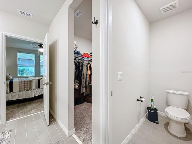 ensuite bathroom with toilet, a walk in closet, and visible vents