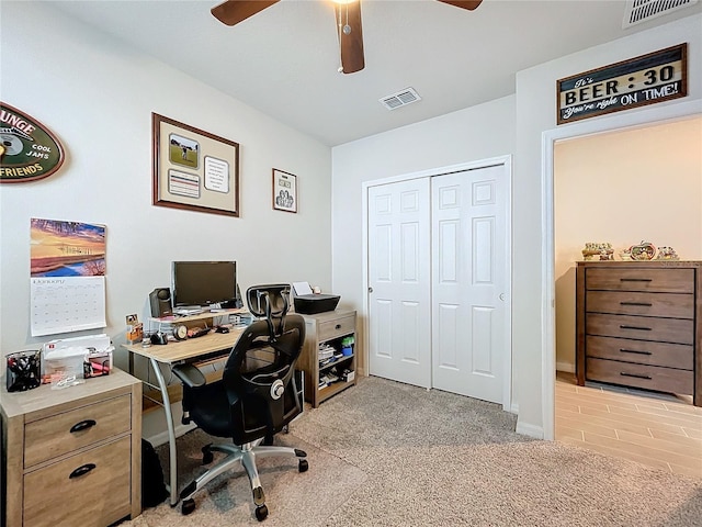 home office with light carpet, ceiling fan, and visible vents