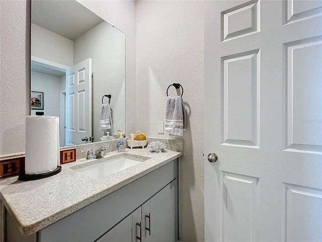 bathroom with a textured wall and vanity