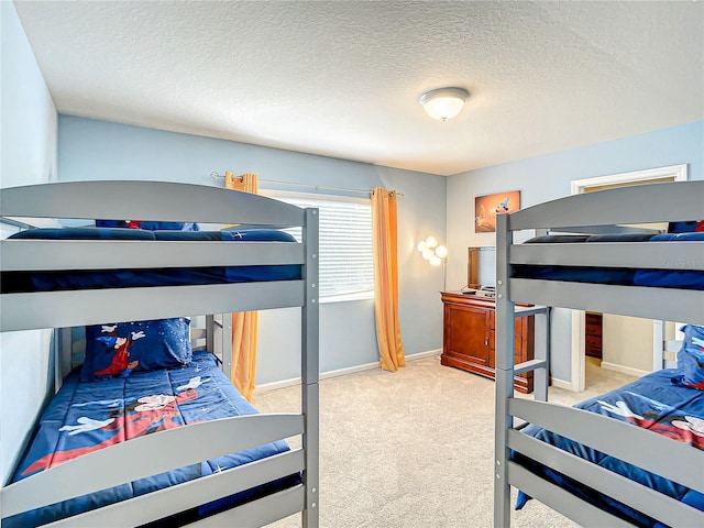 bedroom featuring light carpet, a textured ceiling, and baseboards