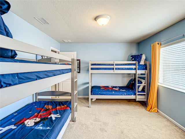 carpeted bedroom featuring visible vents, a textured ceiling, and baseboards