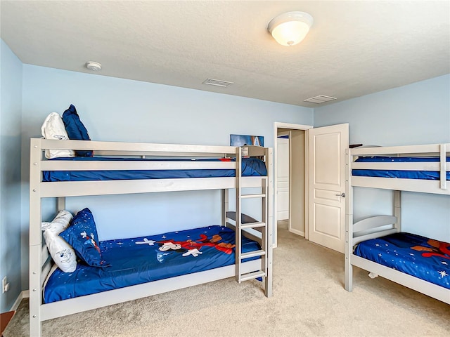 carpeted bedroom featuring a textured ceiling and visible vents