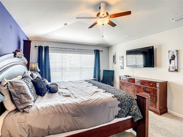 bedroom with light carpet, a textured ceiling, visible vents, and a ceiling fan