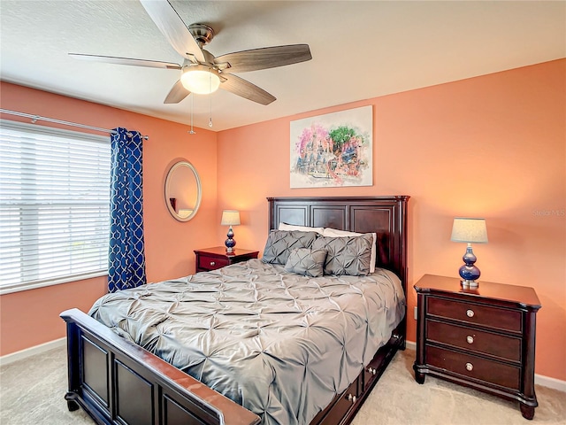 bedroom with a ceiling fan, light carpet, and baseboards