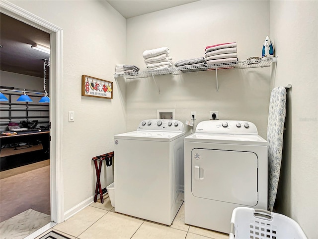 laundry area featuring laundry area, washing machine and dryer, baseboards, and light tile patterned flooring