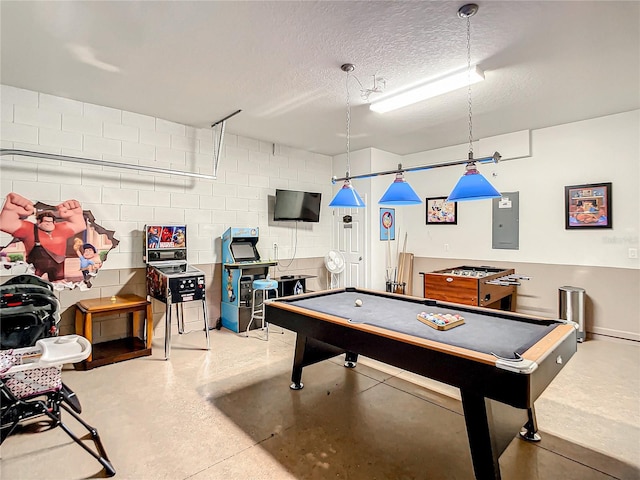 recreation room with a textured ceiling, billiards, concrete block wall, and electric panel