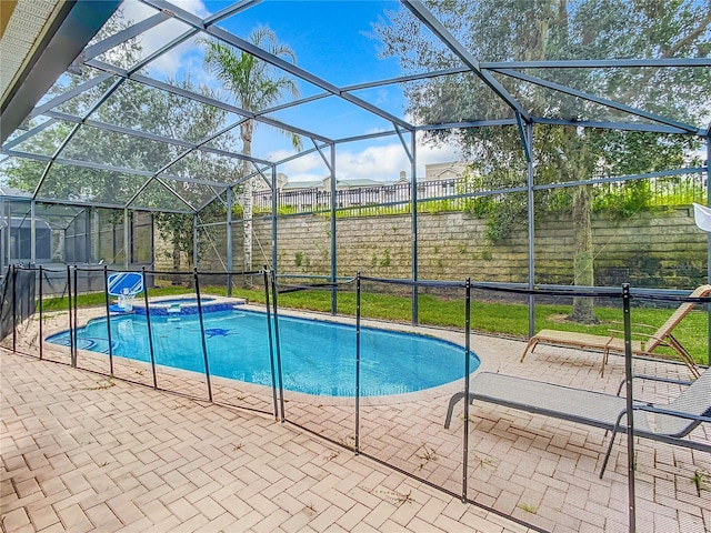 view of pool featuring glass enclosure, a patio area, and a pool with connected hot tub