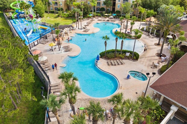 pool with a community hot tub, a water slide, and a patio