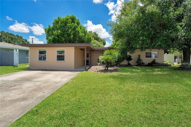 ranch-style house with stucco siding, a front yard, driveway, and fence