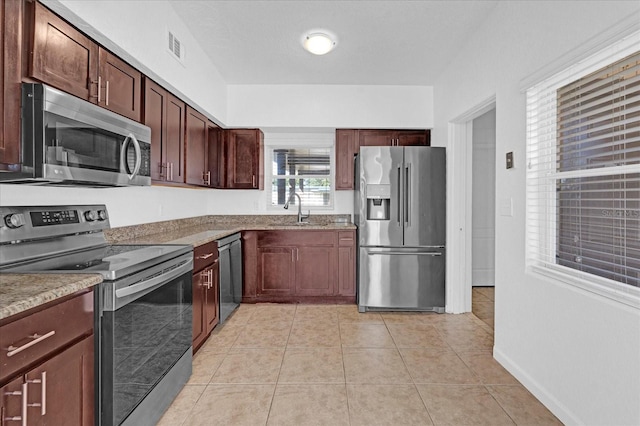 kitchen with light tile patterned floors, baseboards, visible vents, a sink, and appliances with stainless steel finishes